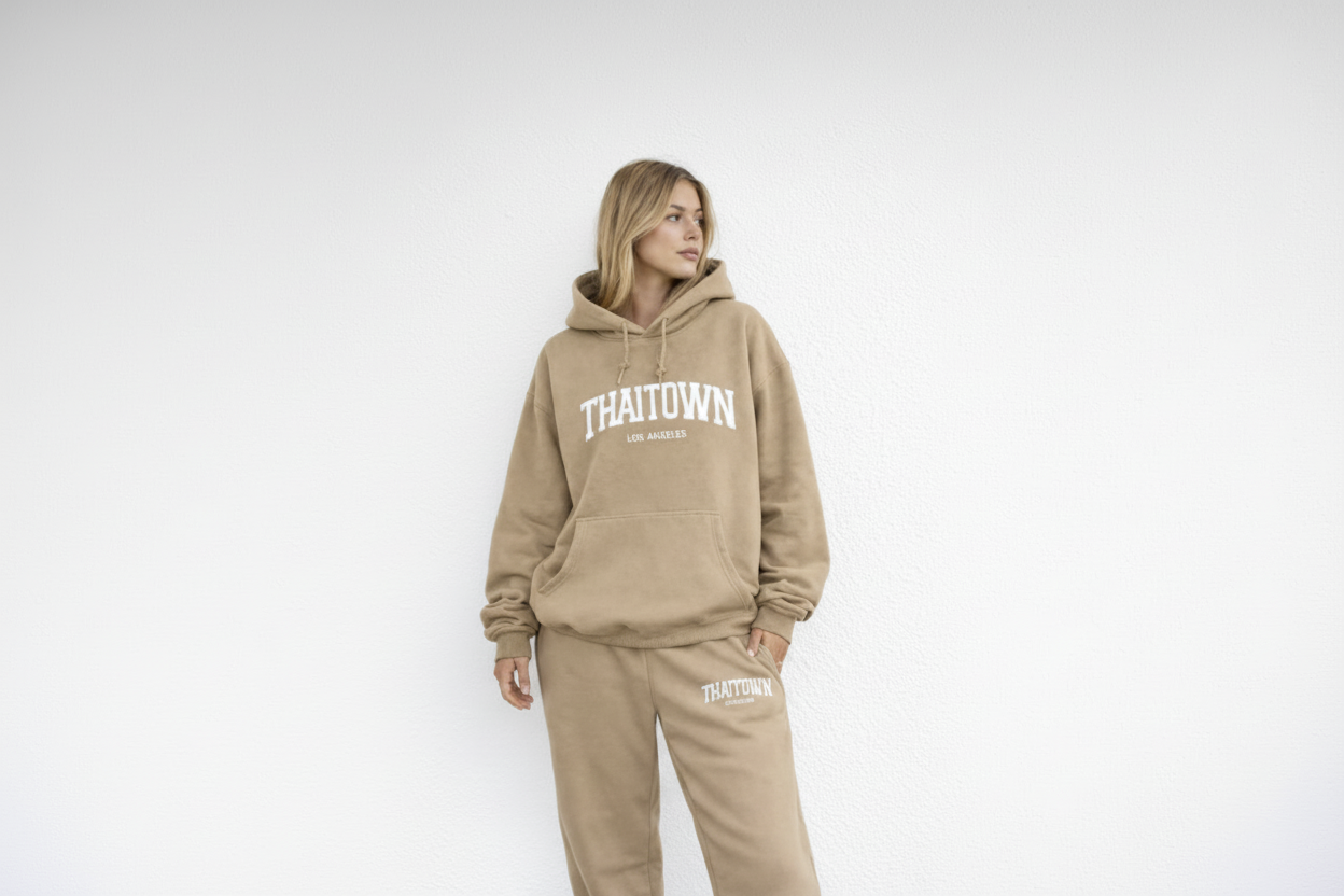 Person wearing a beige 'THAITOWN' hoodie and pants on a white background